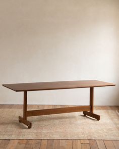 a wooden table sitting on top of a hard wood floor next to a white wall