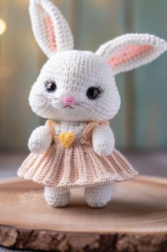 a crocheted bunny doll sitting on top of a piece of wood