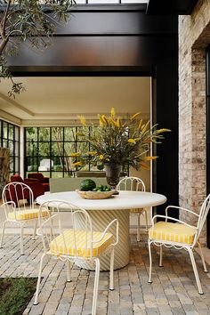 a dining table with yellow chairs and a potted plant in the middle of it