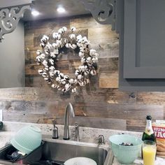 a kitchen sink with a wreath on the wall above it and other items in front of it