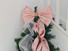 two pink bows tied to the side of a door with pine branches and netting around them