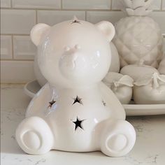 a white teddy bear sitting on top of a counter next to other ceramic figurines