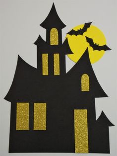 a paper cut out of a house with bats on the roof and a full moon in the background