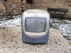 an old computer sitting on top of a rock in front of some water and snow