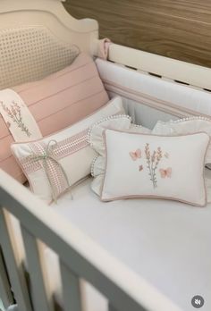 a white crib with pink and gray pillows