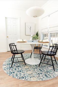 a white table and four chairs in a room with hardwood flooring on the ground