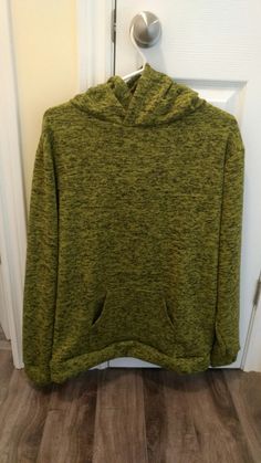 a green hoodie hanging on a door