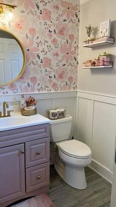 a white toilet sitting next to a sink in a bathroom under a large round mirror