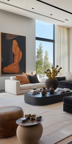 a modern living room with large windows and art on the wall behind the couches