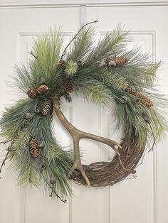 a wreath with antlers and pine cones hanging on a door