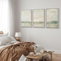 a bedroom with three paintings on the wall