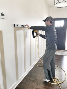 a man using a power drill to paint a wall