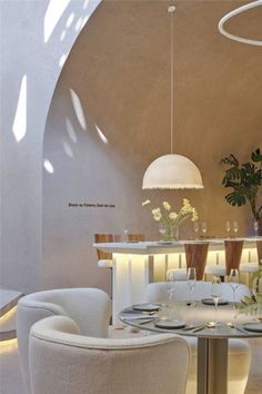 a dining room with white chairs and a round table surrounded by plants in vases