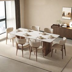 a dining room table with white chairs and plates on it in front of a large window