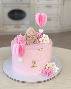 there is a pink cake with flowers and a teddy bear on top that says 2