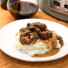 a white plate topped with mashed potatoes covered in beef and gravy next to an instant pot