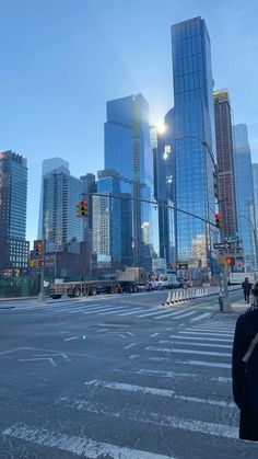 a person standing at an intersection with tall buildings in the background