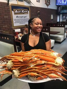 a woman holding a large platter of lobsters