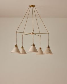 four light chandelier with white shades hanging from the ceiling in an empty room