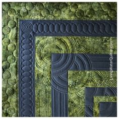 a quilted wall hanging with green and blue designs