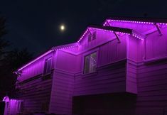 purple lights on the side of a house at night