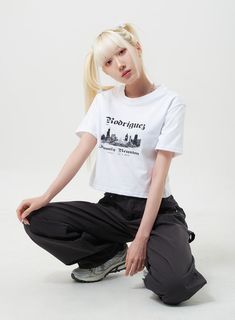 a blonde woman sitting on the ground wearing black pants and a white t - shirt