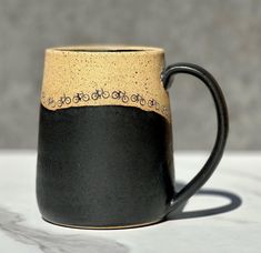 a black and tan coffee mug with writing on it sitting on a white countertop