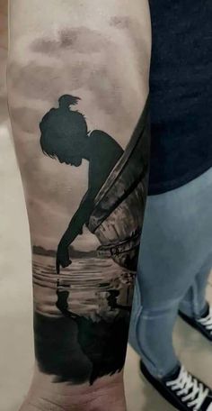 a man's arm with a black and white tattoo of a person on a boat