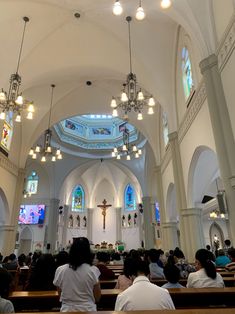 people are sitting in pews at the alter of a church with stained glass windows