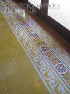 a yellow and white tiled floor next to a window with the words creative cement tile borders