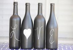 three wine bottles with the word love painted on them