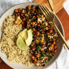 a white plate topped with rice, beans and avocado next to a fork