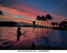 a woman is swimming in the pool at sunset