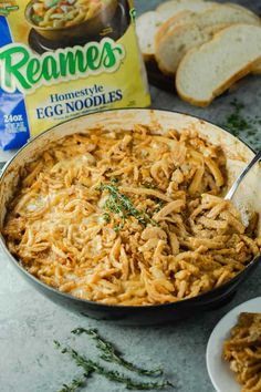 a skillet filled with noodles next to slices of bread