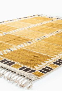 a yellow and black rug with fringes on the bottom is laying on a white surface