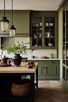 a large kitchen with green cabinets and wooden counter tops, along with hanging lights above the island