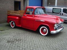 an old red truck parked in front of a building