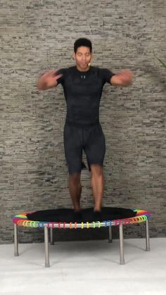 a man standing on top of a trampoline in front of a brick wall