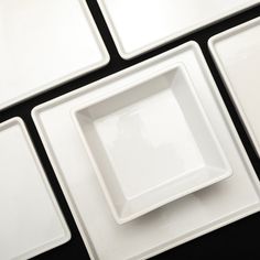 four square white plates sitting next to each other on top of a black countertop