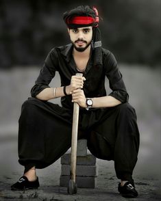 a man sitting on top of a pile of bricks holding a baseball bat and wearing a red bandana