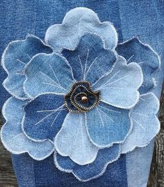 a close up of a blue flower on a piece of denim with gold hardwares