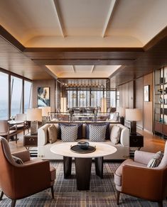 a living room filled with lots of furniture and windows overlooking the ocean in front of it