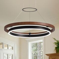 a circular light fixture hanging from the ceiling in a living room with white walls and windows