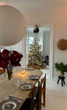 a dining room table is set with place settings for christmas dinner and decorated trees in the background