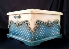 an old blue and white box with polka dots on the lid is sitting on a black surface