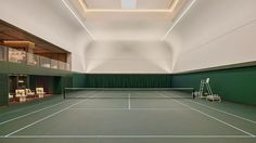 an indoor tennis court with green walls and white lines on the floor, surrounded by chairs