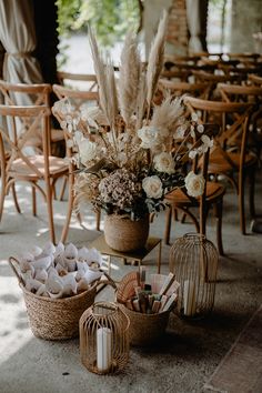 an arrangement of flowers and birdcages on the ground in front of tables with chairs