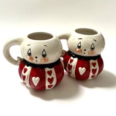 two ceramic mugs with faces and hearts on them