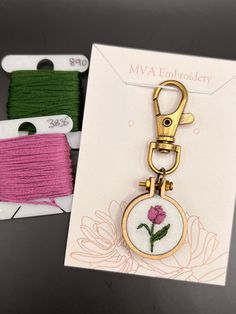 two different colored thread spools and a keychain with a flower on it