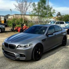 a silver car parked on the side of a road next to other cars in a parking lot